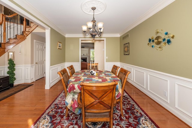 dining area featuring hardwood / wood-style flooring, a notable chandelier, and ornamental molding