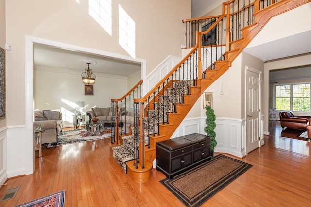 stairway with a high ceiling, crown molding, and wood-type flooring