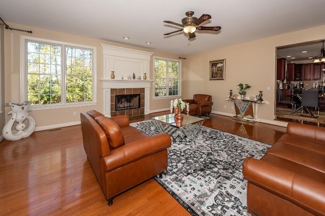 living room featuring ceiling fan, a fireplace, and hardwood / wood-style flooring