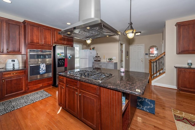 kitchen with a center island, dark stone counters, light hardwood / wood-style floors, appliances with stainless steel finishes, and island range hood