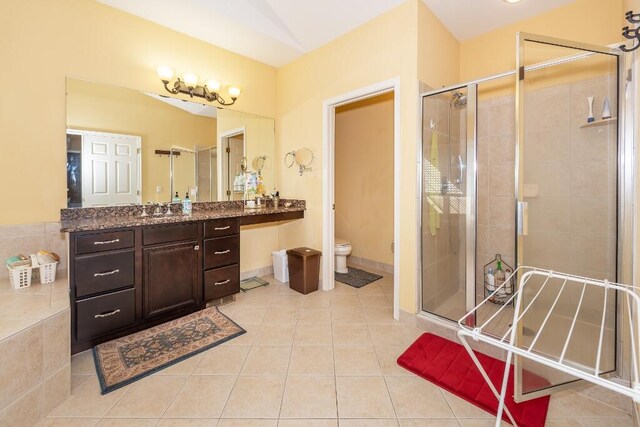 bathroom featuring tile patterned flooring, vanity, toilet, and an enclosed shower