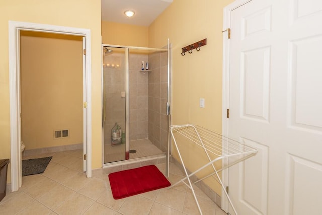 bathroom featuring tile patterned floors, a shower with door, and toilet