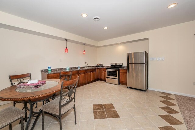 kitchen featuring appliances with stainless steel finishes, dark stone counters, sink, light tile patterned floors, and decorative light fixtures