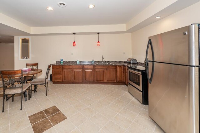 kitchen featuring pendant lighting, dark stone counters, sink, appliances with stainless steel finishes, and kitchen peninsula