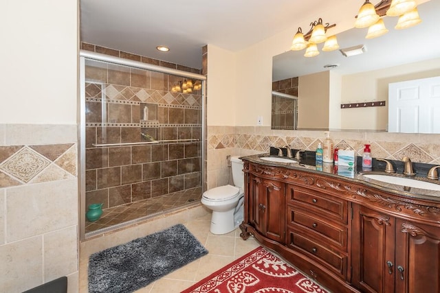 bathroom featuring tile patterned floors, an enclosed shower, toilet, vanity, and tile walls