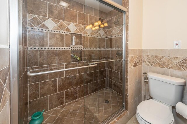 bathroom featuring toilet, walk in shower, and tile walls