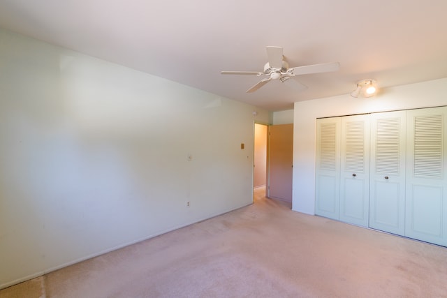 unfurnished bedroom with a closet, light colored carpet, and ceiling fan