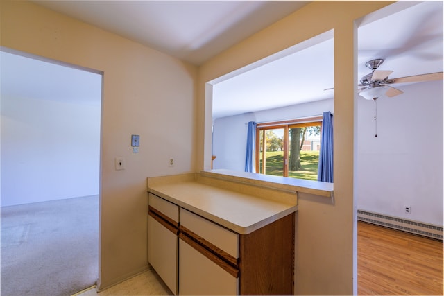 interior space with ceiling fan, light wood-type flooring, and a baseboard heating unit