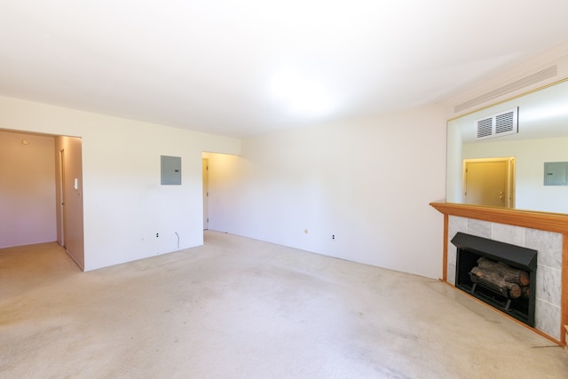 unfurnished living room featuring electric panel, light colored carpet, and a tiled fireplace