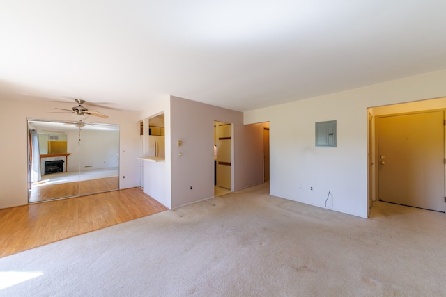 unfurnished living room with electric panel, ceiling fan, and light colored carpet