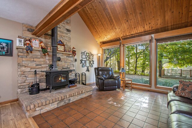 living room with tile patterned flooring, plenty of natural light, beam ceiling, and a wood stove