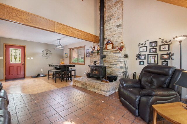 living room with beamed ceiling, hardwood / wood-style floors, a towering ceiling, and a wood stove