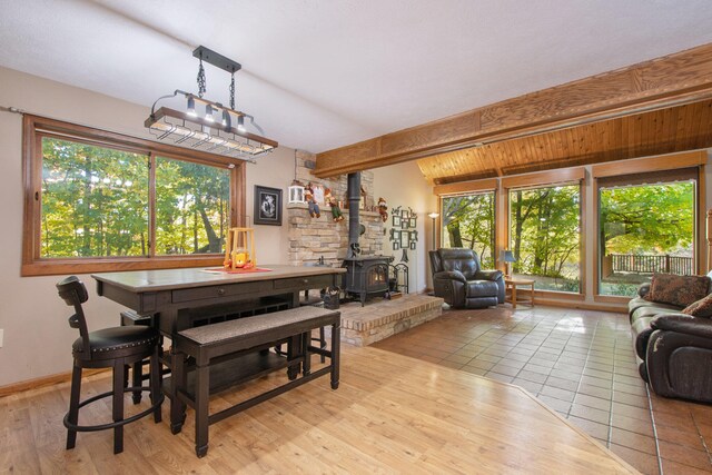 tiled dining space with a wood stove and vaulted ceiling with beams