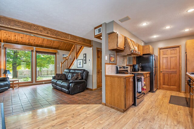 kitchen with backsplash, a textured ceiling, appliances with stainless steel finishes, beamed ceiling, and light hardwood / wood-style floors