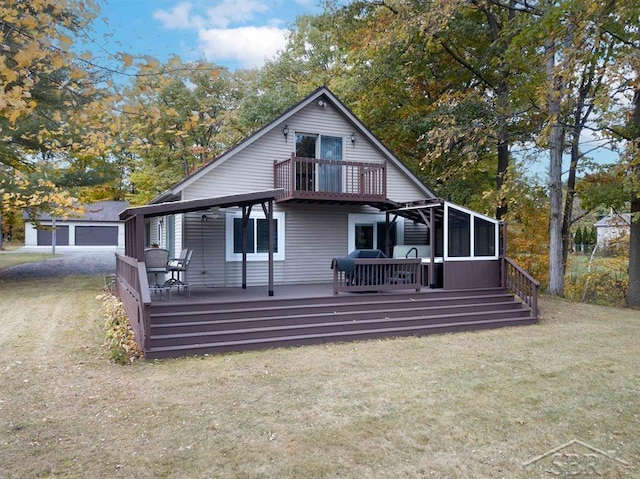 rear view of property featuring a sunroom, a wooden deck, and a lawn