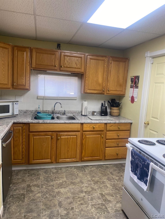 kitchen featuring white appliances, backsplash, a drop ceiling, and sink