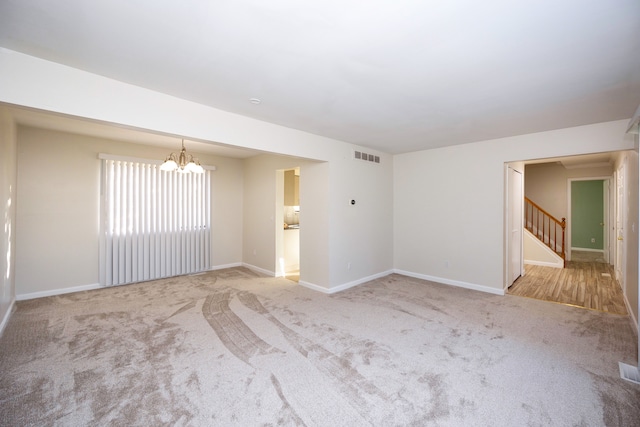 carpeted empty room with a chandelier