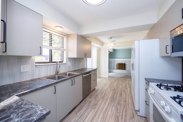 kitchen with sink, stainless steel appliances, light hardwood / wood-style flooring, a chandelier, and pendant lighting