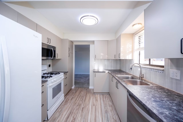 kitchen with backsplash, stainless steel appliances, sink, white cabinets, and light hardwood / wood-style floors