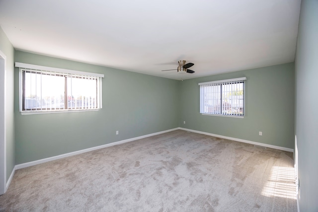 spare room with ceiling fan, light carpet, and a wealth of natural light