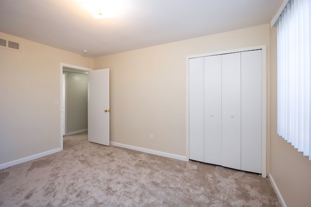 unfurnished bedroom featuring light carpet and a closet