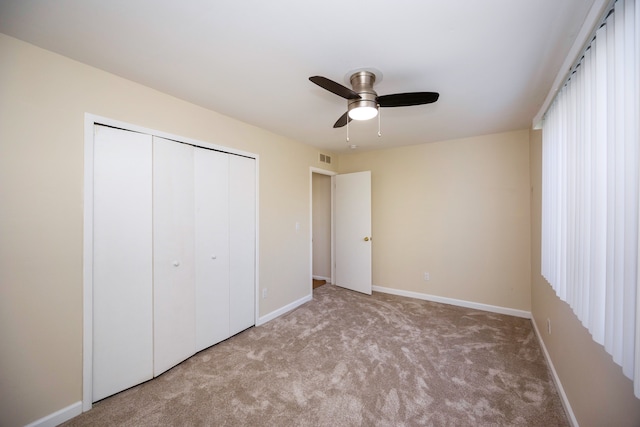 unfurnished bedroom featuring light carpet, a closet, and ceiling fan