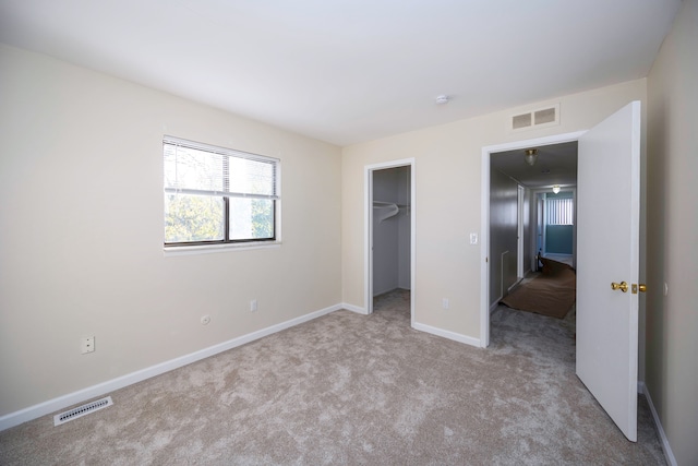 unfurnished bedroom featuring light carpet, a spacious closet, and a closet