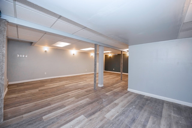 basement featuring a paneled ceiling and wood-type flooring