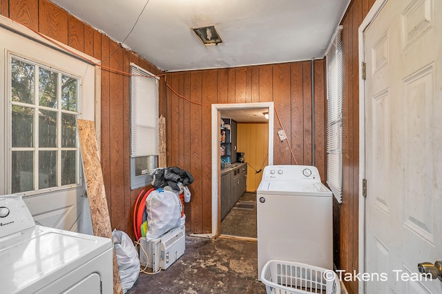 clothes washing area with washing machine and clothes dryer and wood walls