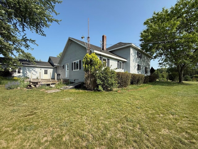 2702 E Hoague Rd, Michigan, MI 49411 - view of side of property featuring a deck, a chimney, and a yard