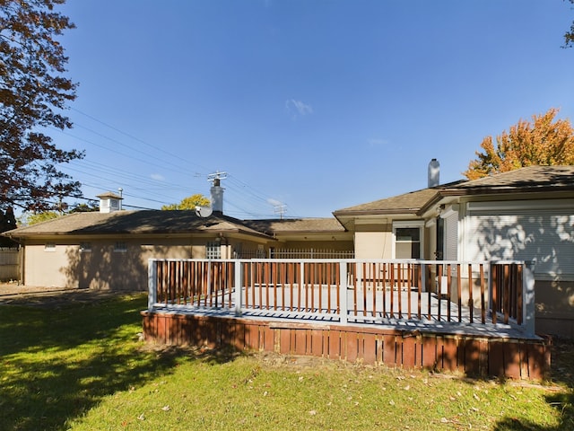 rear view of property featuring a lawn and a deck