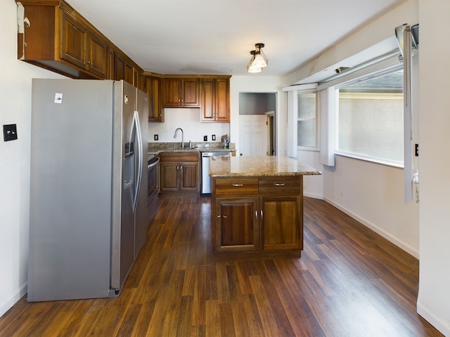 kitchen with a kitchen island, sink, dark wood-type flooring, and appliances with stainless steel finishes