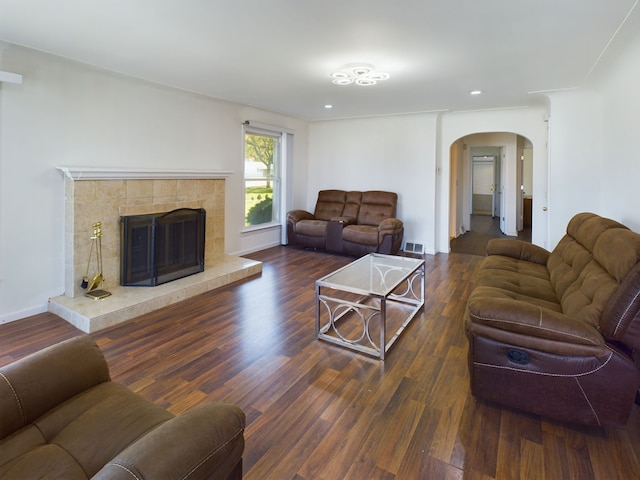 living room featuring dark wood-type flooring and a tiled fireplace