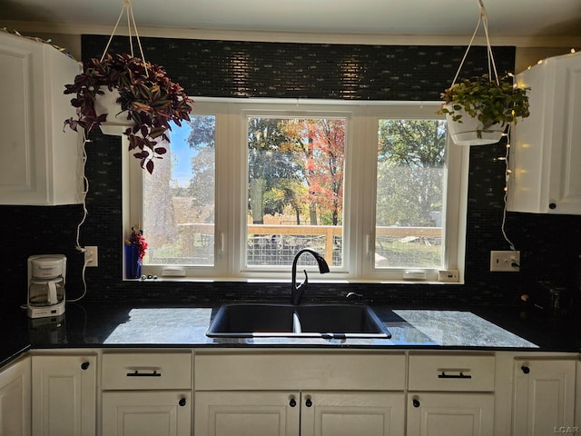 kitchen featuring white cabinets, backsplash, and sink