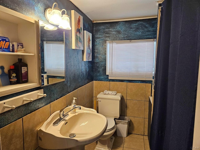 bathroom with toilet, tile patterned floors, tile walls, and sink