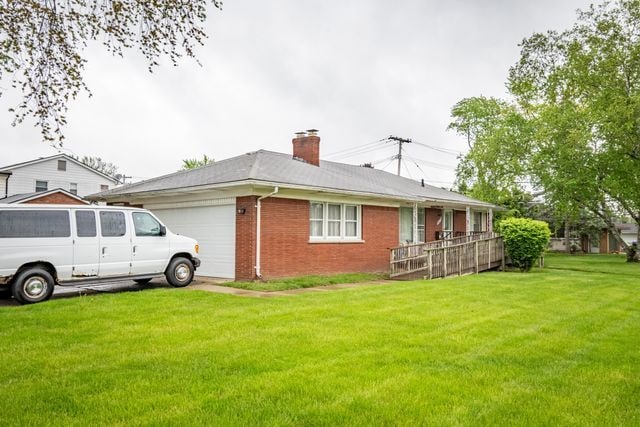 25672 Avondale St, Dearborn Heights, MI 48125 - view of side of home featuring a garage, a chimney, brick siding, and a lawn