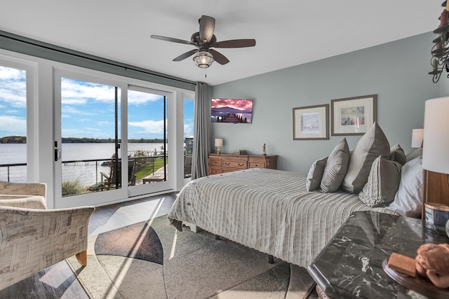 bedroom with access to outside, multiple windows, ceiling fan, and a water view