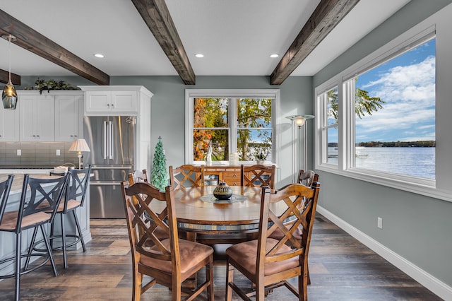 dining area featuring dark hardwood / wood-style flooring, beamed ceiling, and a water view