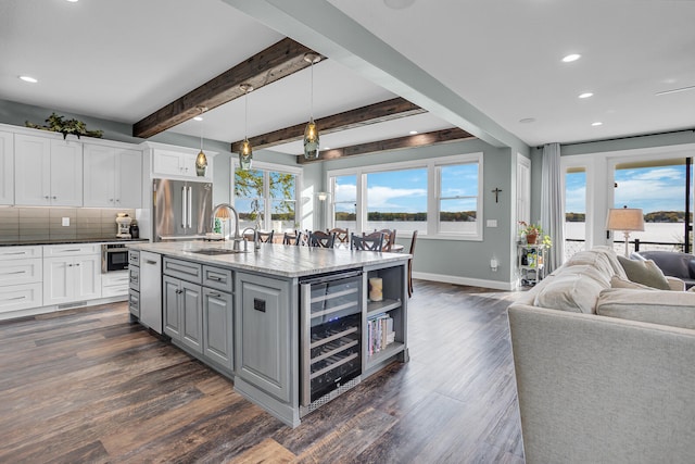 kitchen with white cabinets, stainless steel appliances, hanging light fixtures, and beamed ceiling