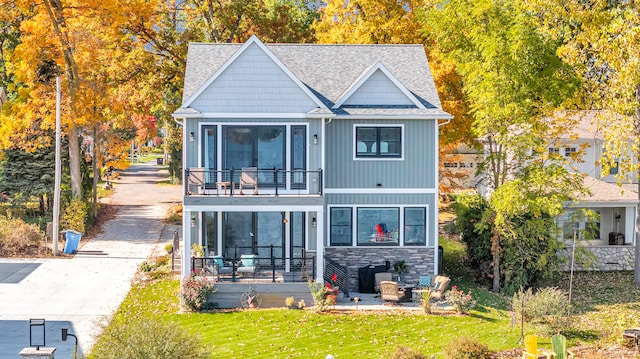 rear view of house featuring a balcony and a lawn