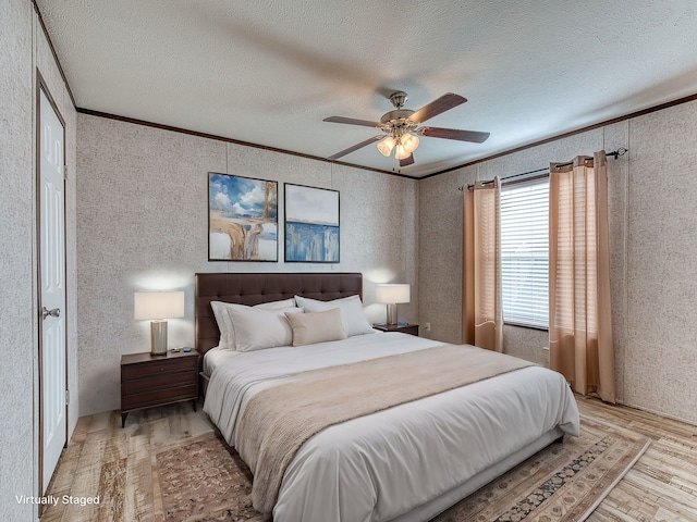 bedroom featuring a textured ceiling, light hardwood / wood-style flooring, ceiling fan, and ornamental molding