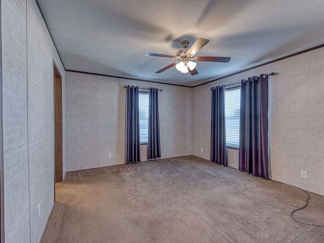 carpeted spare room featuring a textured ceiling, ceiling fan, and crown molding