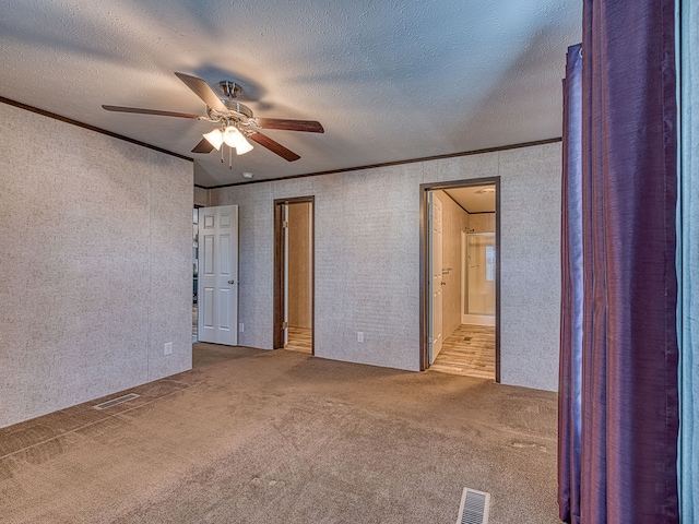 carpeted empty room featuring a textured ceiling, ceiling fan, and crown molding