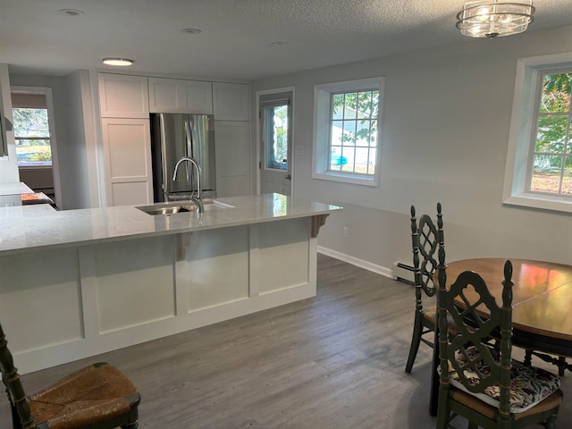 kitchen featuring sink, stainless steel refrigerator, dark wood-type flooring, and light stone counters