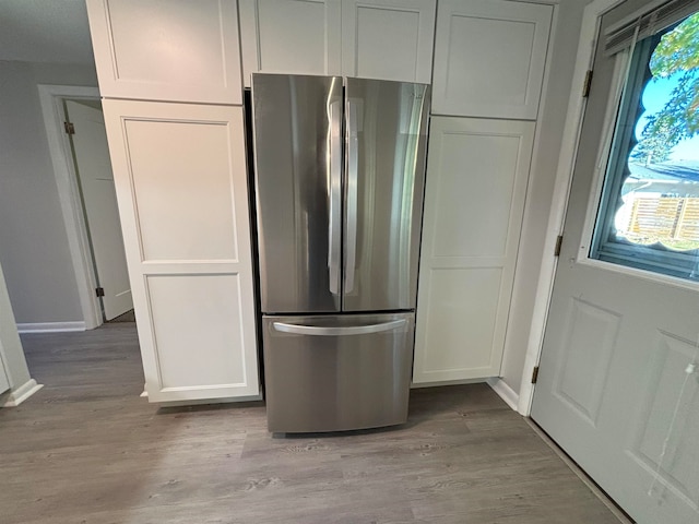 kitchen featuring white cabinets, light hardwood / wood-style flooring, and stainless steel refrigerator