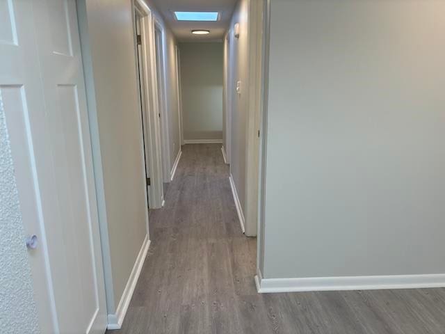 hallway with a skylight and hardwood / wood-style flooring