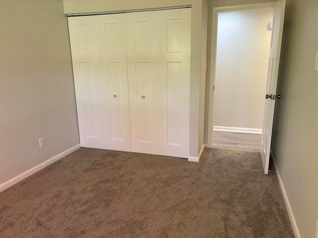 unfurnished bedroom with dark carpet and a closet