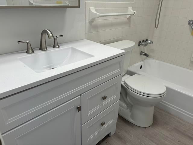 full bathroom with toilet, vanity, hardwood / wood-style flooring, and tiled shower / bath combo