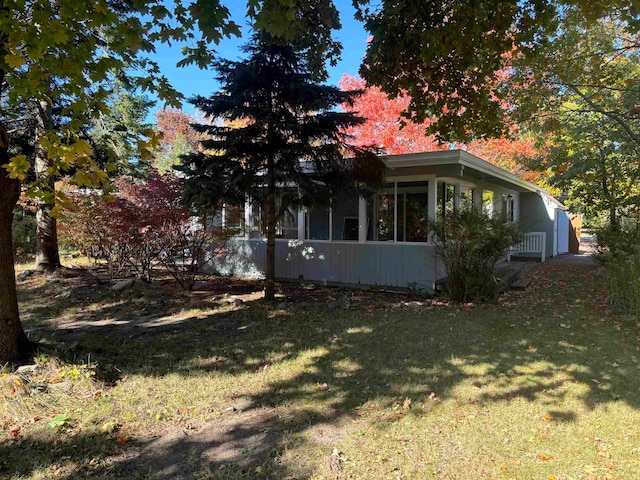 view of side of home with a lawn and a sunroom