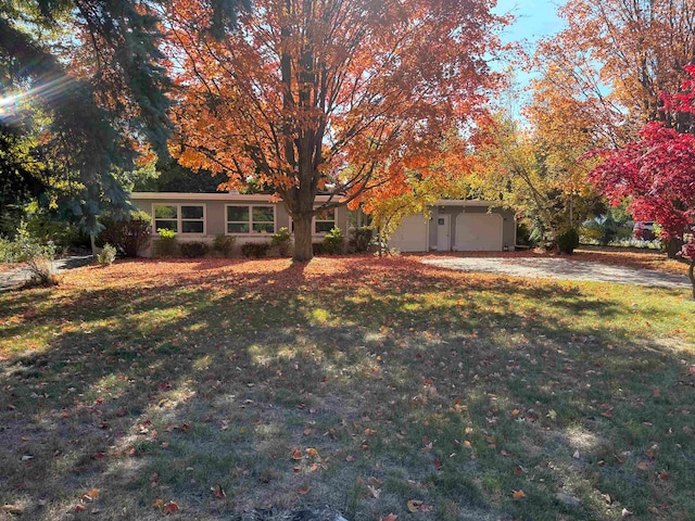 view of property hidden behind natural elements featuring a garage and a front yard